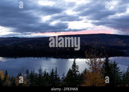 Blick auf einen Hügel auf der anderen Seite des see bei einem blauen Sonnenuntergang Stockfoto