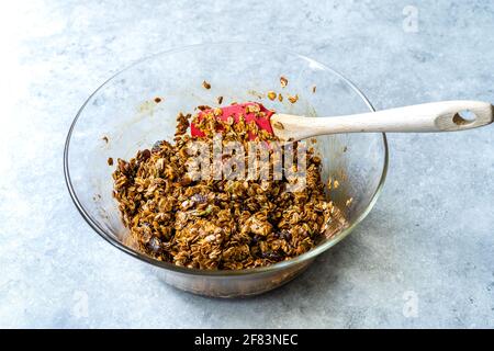 Hausgemachtes, gebackenes Müsli mit Melasse, Rosinen und Nüssen in einer Glasschüssel. Einsatzbereit. Stockfoto