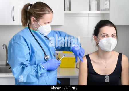 Junge Frau mit schützender Gesichtsmaske wird geimpft, Coronavirus-Konzept. Hochwertige Fotos Stockfoto