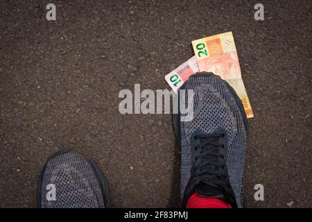 Auf brasilianisches Geld zu treten. Konzept Bild der brasilianischen Wirtschaft. Stockfoto