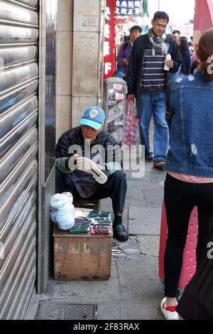 Hong Kong Szene mit einem alten Mann, der in Mongkok Schuhe repariert Stockfoto