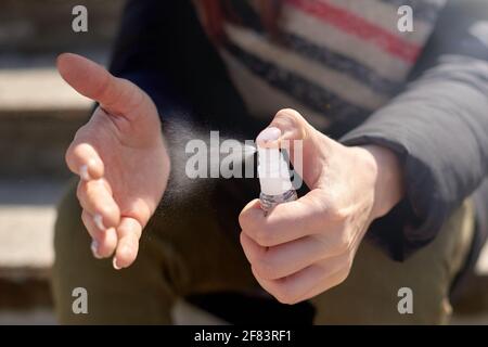 Handdesinfektionsmittel Alkohollösung in der Flasche mit Spender. Transparentes Antiseptikum in den Händen auf der Straße. Anwendung von Alkoholspray Stockfoto