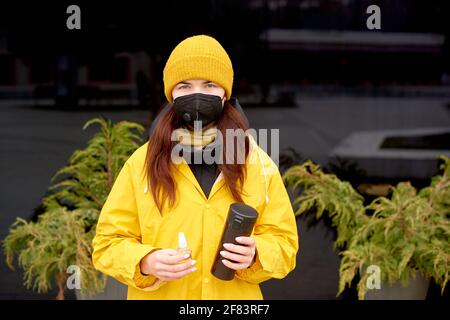 Frau in medizinischer Maske, mit Desinfektionsmittel in der Hand in Quarantänezeit, Restaurants geschlossen. Getränke und Lebensmittel zum Mitnehmen. Unterstützung für Unternehmer Stockfoto