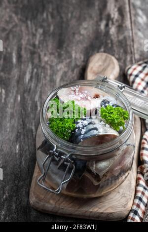 Makrelen in Salzlake mit Zwiebeln und Gewürzen im Glasgefäß Auf Holztisch Stockfoto