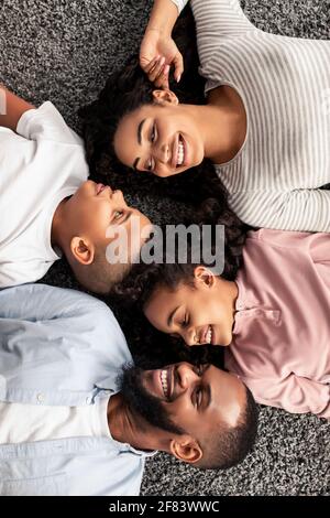 Porträt einer schwarzen Familie, die zusammen auf dem Boden liegt Stockfoto