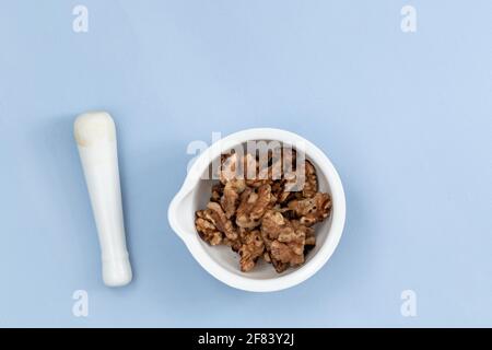Gruppe von Walnüssen in einer weißen Schale auf blauem Hintergrund Stockfoto