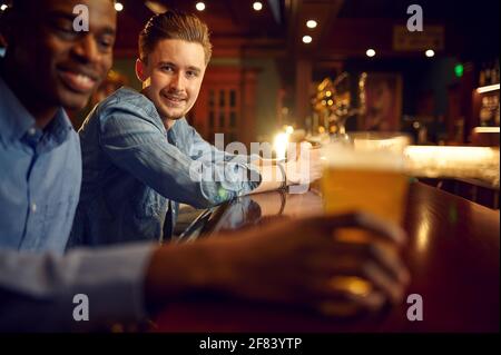 Zwei männliche Freunde lassen sich am Tresen in der Bar ausklingen Stockfoto