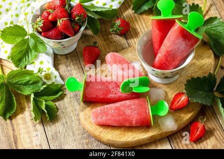 Sommerdessert. Hausgemachter Erdbeer-Fruchtsaft, Erdbeer-Eis oder Erdbeerpopsicles auf einem rustikalen Tisch. Stockfoto