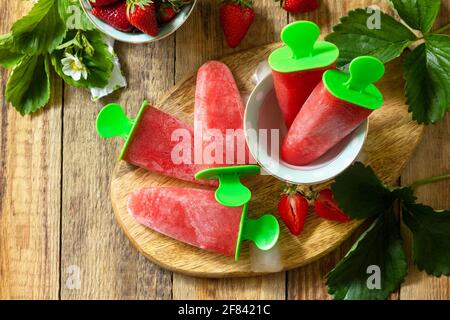 Sommerdessert. Hausgemachter Erdbeer-Fruchtsaft, Erdbeer-Eis oder Erdbeerpopsicles auf einem rustikalen Tisch. Stockfoto