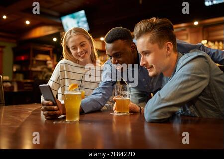 Freunde sehen sich Fotos am Telefon in der Bar an Stockfoto