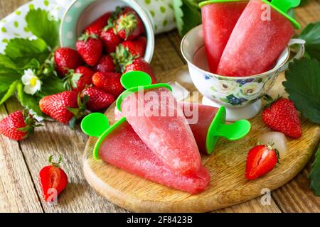 Sommerdessert. Hausgemachter Erdbeer-Fruchtsaft, Erdbeer-Eis oder Erdbeerpopsicles auf einem rustikalen Tisch. Stockfoto