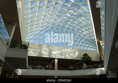 Grodno, Weißrussland - 07. April 2021: Das Innere des modernen großen Einkaufs- und Unterhaltungskomplexes Trinity mit transparentem Glasdach. Stockfoto