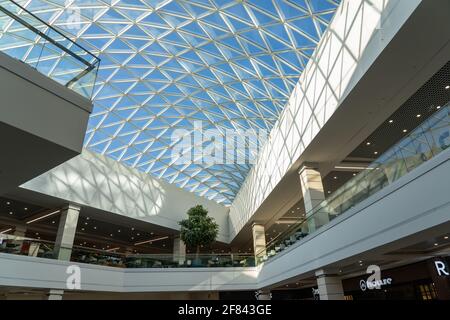 Grodno, Weißrussland - 07. April 2021: Das Innere des modernen großen Einkaufs- und Unterhaltungskomplexes Trinity mit transparentem Glasdach. Stockfoto