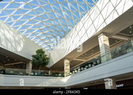 Grodno, Weißrussland - 07. April 2021: Das Innere des modernen großen Einkaufs- und Unterhaltungskomplexes Trinity mit transparentem Glasdach. Stockfoto