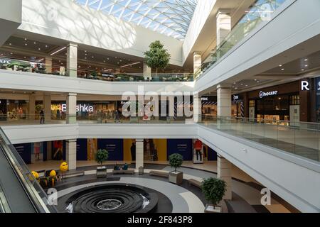 Grodno, Weißrussland - 07. April 2021: Das Innere des modernen großen Einkaufs- und Unterhaltungskomplexes Trinity mit transparentem Glasdach. Stockfoto