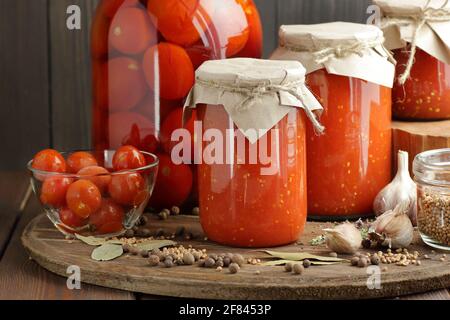 Konserve hausgemachtes Tomatenmark und eingelegte Tomaten in Kunststoff-freie Gläser auf rustikalen Tisch in Speisekammer, Nahaufnahme, cottagecore, einfache Wohnästhetik, zu Hause Stockfoto