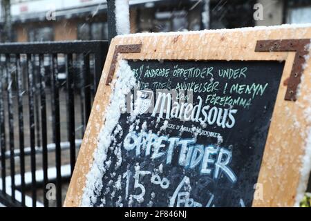 Ein Restaurant im Freien während des Schneesturms, der am Sonntag über Östergötland einzog. Ein Schild zeigt die Öffnungszeiten während der Coronapandemie. Stockfoto