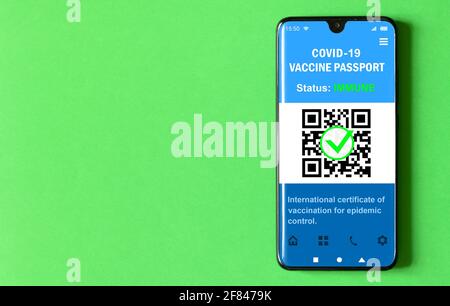 Digitaler Gesundheitspass der COVID-19-Impfung im Mobiltelefon auf grünem Hintergrund, Pass-App im Smartphone für Reisen. Coronavirus-Impfstoff Certif Stockfoto