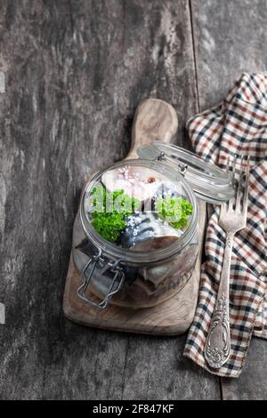 Makrelen in Salzlake mit Zwiebeln und Gewürzen im Glasgefäß Auf Holztisch Stockfoto