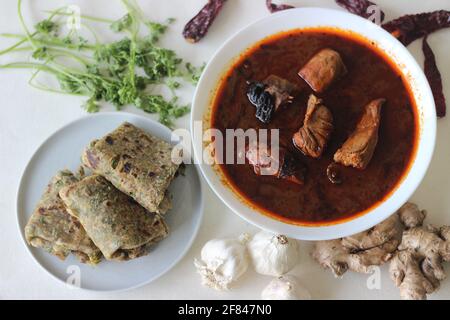 Indisches Fladenbrot aus Vollkornmehl mit gemahlenem Leinsamen und frischen Korianderblättern, serviert mit rotem Soße-Fischcry. Lokal bekannt als cor Stockfoto