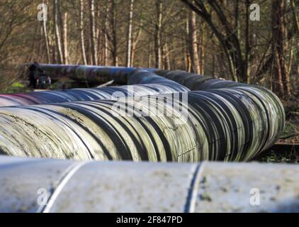 Potsdam, Deutschland. April 2021. Dicke, graue Fernwärmerohre liegen zwischen der Autobahn Nuthe und der Autobahn Nuthe am Rande eines Weges im Wald. Quelle: Soeren Stache/dpa-Zentralbild/ZB/dpa/Alamy Live News Stockfoto