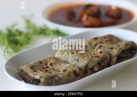 Indisches Fladenbrot aus Vollkornmehl mit gemahlenem Leinsamen und frischen Korianderblättern, serviert mit Red Gravy Fish-Corry. Lokal bekannt als cori Stockfoto