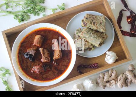 Indisches Fladenbrot aus Vollkornmehl mit gemahlenem Leinsamen und frischen Korianderblättern, serviert mit Red Gravy Fish-Corry. Lokal bekannt als cori Stockfoto