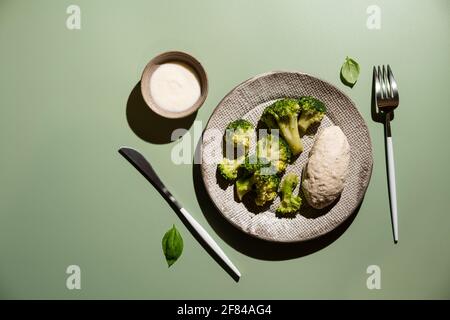 Gesundes, ausgewogenes Mittagessen. Hähnchenburger mit Brokkoli auf hellgrünem Hintergrund, Draufsicht. Gesunde Ernährung Lifestyle-Konzept Stockfoto