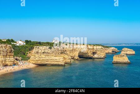 Blick auf Klippen aus zerklüfteten Sandsteinfelsen, Felsformationen im türkisfarbenen Meer, Sandstrand auf der Klippe, Praia da Marinha, Algarve, Lagos, Portugal Stockfoto