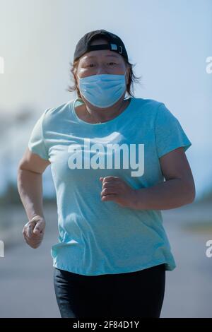 Reife asiatische Frau läuft und schaut auf die Kamera Stockfoto