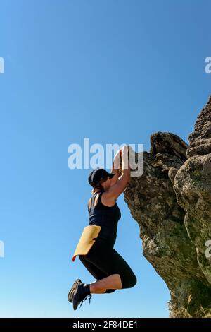 Die Frau ist im Bergsteigen engagiert, klettert bis zur Spitze, eine epische Ansicht des Bergsteigers gegen den Himmel und die Berge.2020 Stockfoto