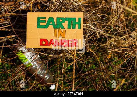 Bunter Earth in Danger Titel auf Pappplakat. Draufsicht. Kunststoffflasche. Stockfoto