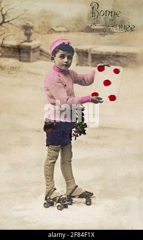 'Bonne Annee' Frohes Neues Jahr in Französisch-ca. 1910 handkolorierte Fotopostkarte eines Jungen auf Rollschuhe im Winter mit einer Karte mit Rosen oben. Stockfoto