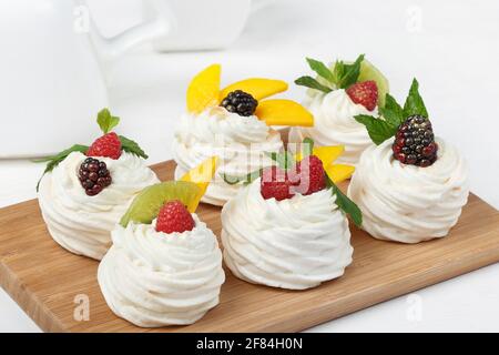 Hausgemachte Mini-pavlova-Kuchen mit Schlagsahne und frischen Beeren Auf hellem Hintergrund Stockfoto