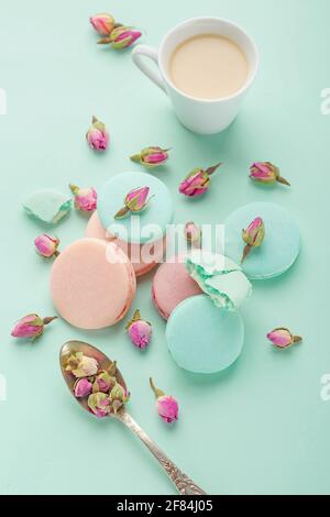 Kaffeetasse und farbenfrohes Macaron auf pastellfarbenem Hintergrund, Draufsicht. Gemütliches Frühstück am Morgen. Modische, flache Lay-Optik. Süße Makronen. Stockfoto