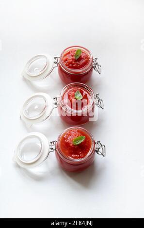 Hausgemachte Tomatensauce mit Basilikum in Gläsern isoliert auf weißem Hintergrund. Direkt darüber. Stockfoto