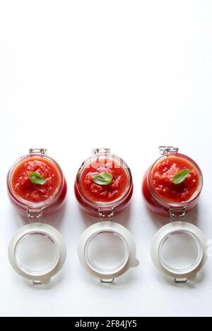 Hausgemachte Tomatensauce mit Basilikum in Gläsern isoliert auf weißem Hintergrund. Direkt darüber. Stockfoto