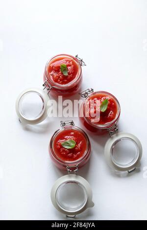Hausgemachte Tomatensauce mit Basilikum in Gläsern isoliert auf weißem Hintergrund. Direkt darüber. Stockfoto