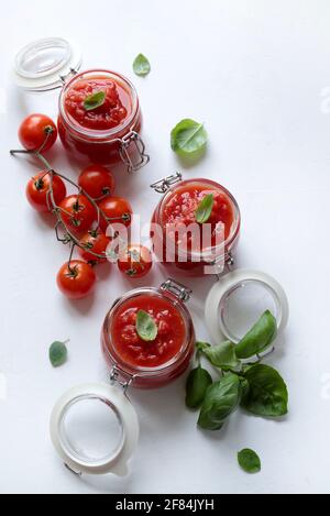 Hausgemachte Tomatensauce mit Basilikum in Gläsern isoliert auf weißem Hintergrund. Direkt darüber. Stockfoto