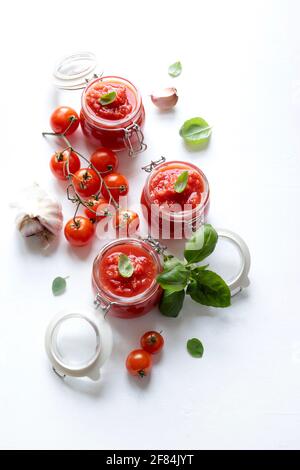 Hausgemachte Tomatensauce mit Basilikum in Gläsern isoliert auf weißem Hintergrund. Direkt darüber. Stockfoto
