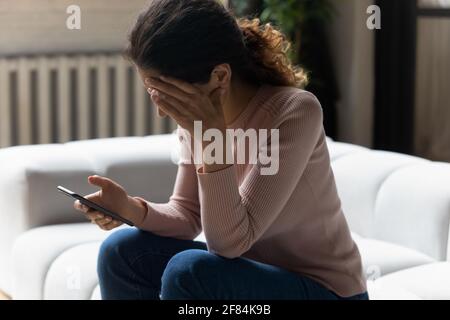 Gestresste junge latinerin bekommt eine böse Erpressung per E-Mail Stockfoto