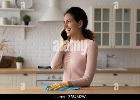 Positive junge Frau genießt Telefongespräche während der Hausarbeit Stockfoto