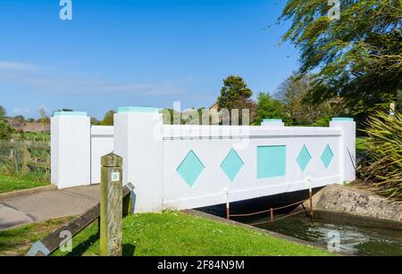 Kleine Fußgängerbrücke im Art déco-Stil über das Wasser im Mewsbrook Park, Littlehampton, West Sussex, England, Großbritannien. Stockfoto