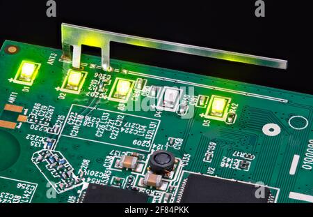 Kleine interne WLAN-Antenne und leuchtende LED-Leuchten auf der Platine. Leuchtdioden, Kondensatoren und Induktoren in grüner Leiterplattendetail. Technik. Stockfoto