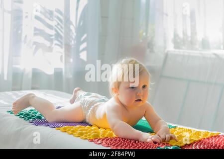 Das Baby liegt mit dem Bauch nach unten auf den Massagematten. Nahaufnahme. Stockfoto