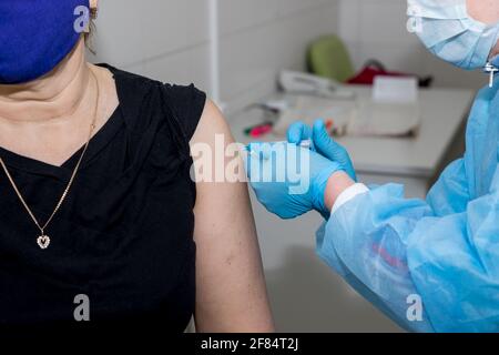 Arzt mit Spritze doing Injektionsimpfstoff, Grippe, Influenza in der Schulter von Ältere Frau, junge Krankenschwester, die ältere Patienten injiziert, impft Stockfoto