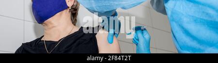 Arzt mit Spritze doing Injektionsimpfstoff, Grippe, Influenza in der Schulter von Ältere Frau, junge Krankenschwester, die ältere Patienten injiziert, impft Stockfoto