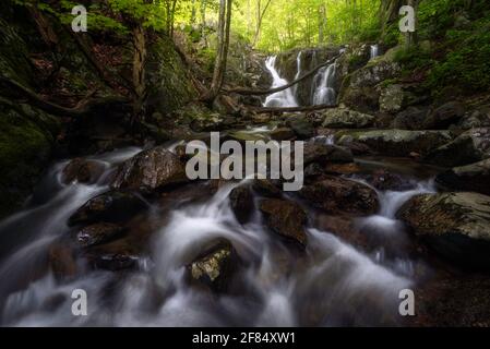 Kleine Kaskaden mit den Rose River Falls im Hintergrund im Central District des Shenandoah National Park an einem frühen Junitag. Stockfoto