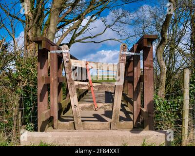 Ein Konzerttor auf einer Fußgängerbrücke auf einem Landwanderweg. Die drei Querbalken sind durch eine Metallstange verbunden, die es ihnen ermöglicht, sie hochzuheben Stockfoto