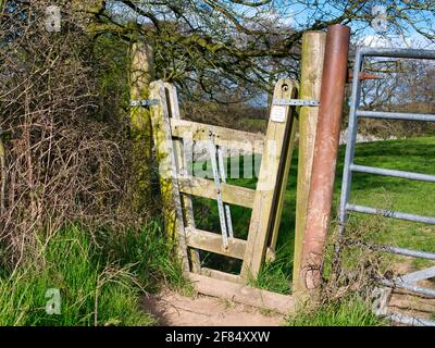 Ein Konzerttor zwischen zwei Feldern auf einem Landwanderweg. Die drei Querbalken sind durch eine Metallstange verbunden, die es erlaubt, sie zu heben Stockfoto